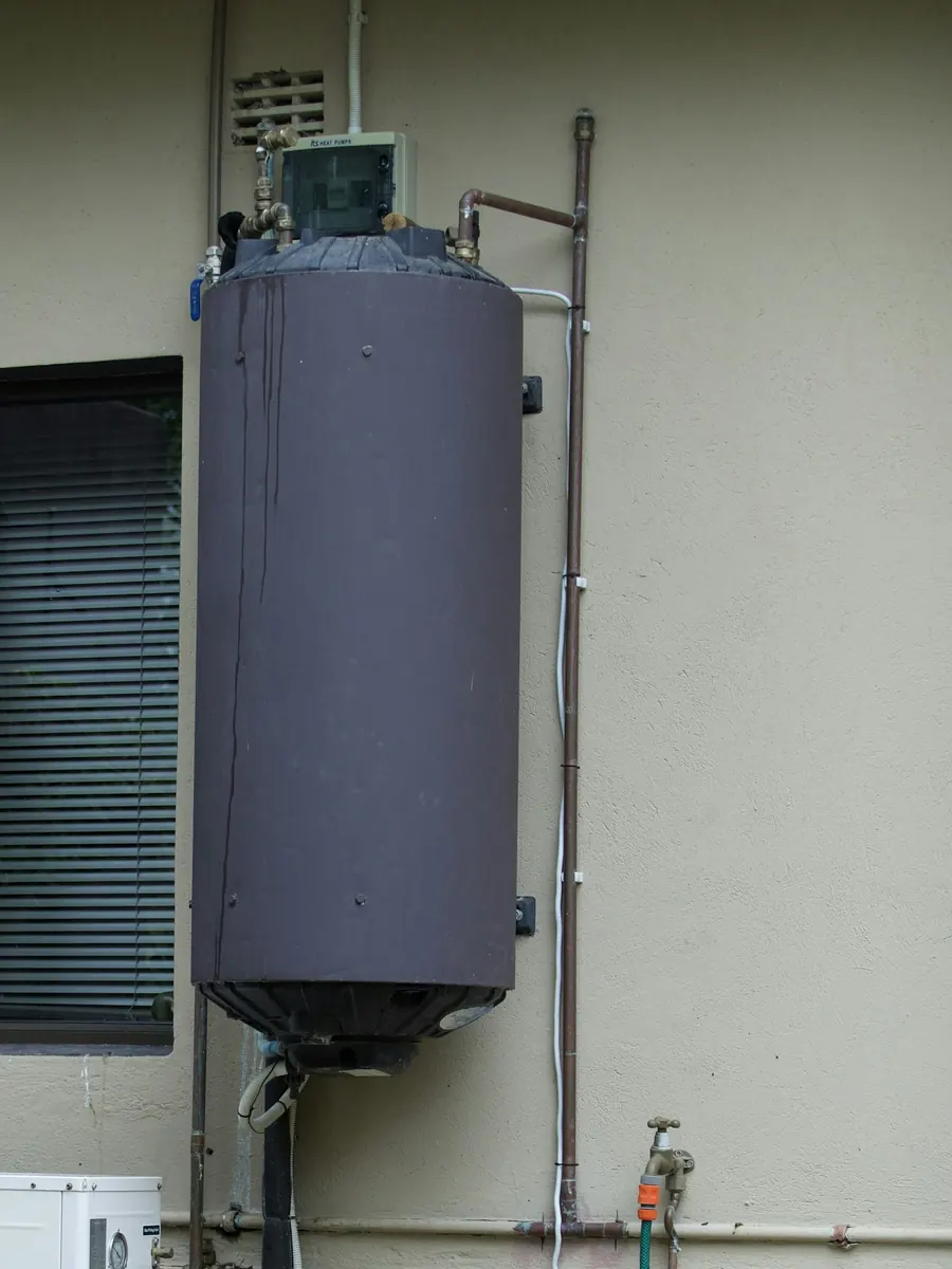 Residential tank water heater mounted on an exterior wall